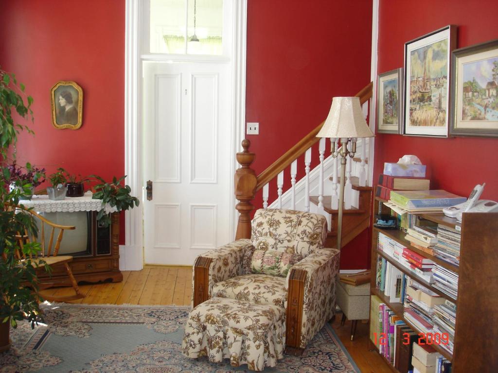Saint-Luc-de-Vincennes姐妹别墅旅馆的客厅设有红色的墙壁和椅子