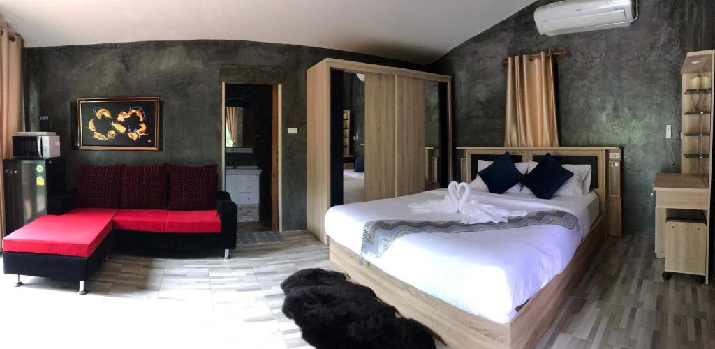 湄登Rai Phusaitran ไร่ภูสายธาร的一间卧室配有一张大床和一张红色的沙发
