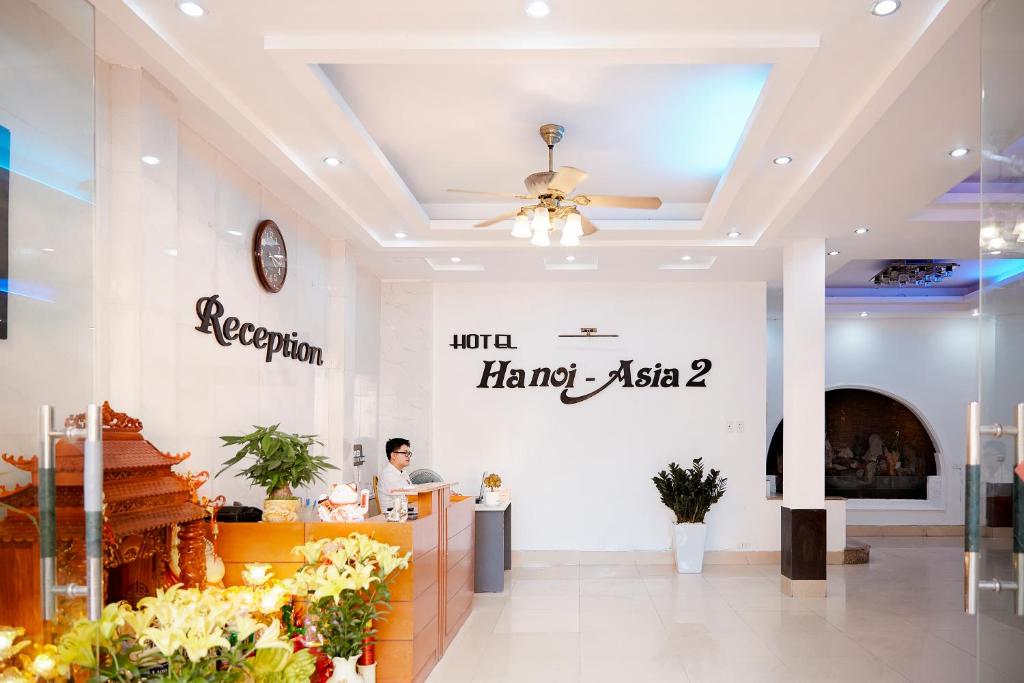 河内Hanoi Asia 2 Long Bien的坐在柜台上的男人的商店