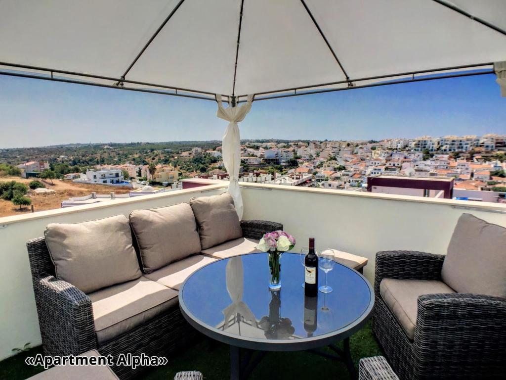 费拉古多Apartment Alpha - 2 Bedrooms, Private Rooftop Patio with Hot Tub, BBQ and View的天井配有桌子、两把椅子和遮阳伞。