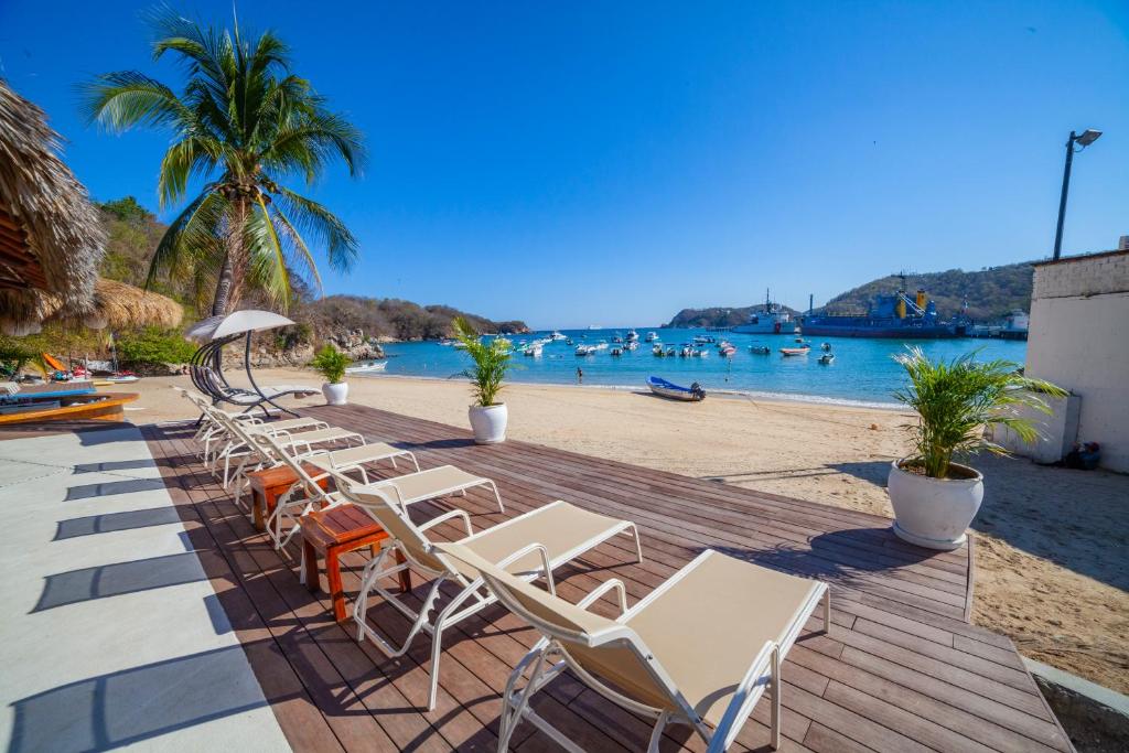 圣克鲁斯华特库Hotel Marina Resort & Beach Club的海滩旁的木甲板上摆放着一排椅子