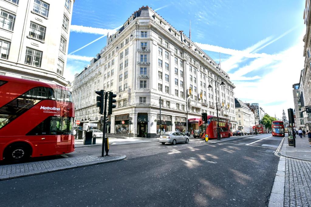 伦敦斯特兰德宫酒店的一辆红色双层巴士沿着城市街道行驶