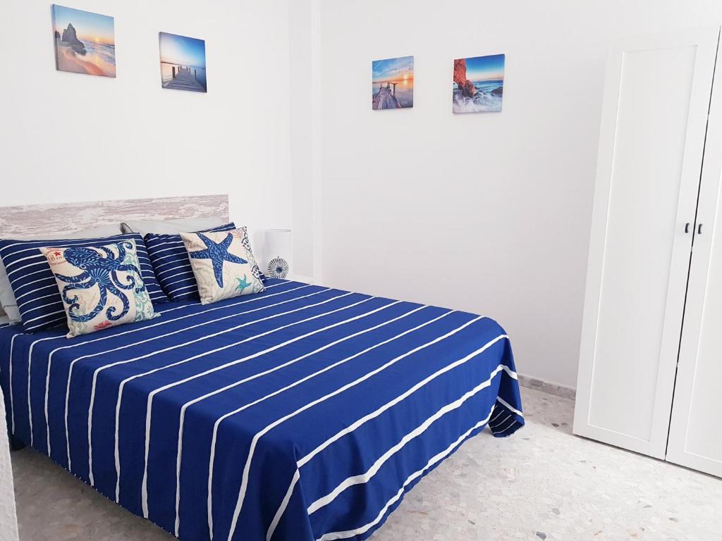 科尼尔-德拉弗龙特拉Conil Centro & Playa, descanso perfecto, Aire Ac y WIFI -SOLO FAMILIAS Y PAREJAS-的卧室配有蓝色和白色条纹床