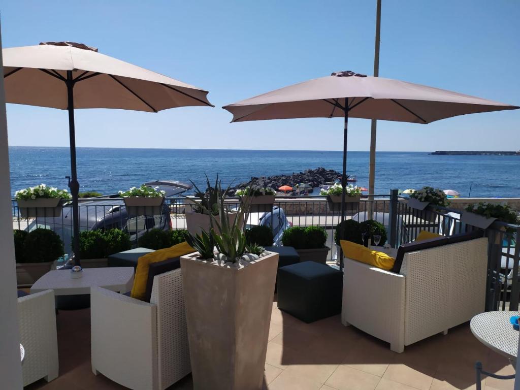 贾迪尼-纳克索斯ZI DIMA APARTMENTS的一个带桌子和遮阳伞的庭院和大海