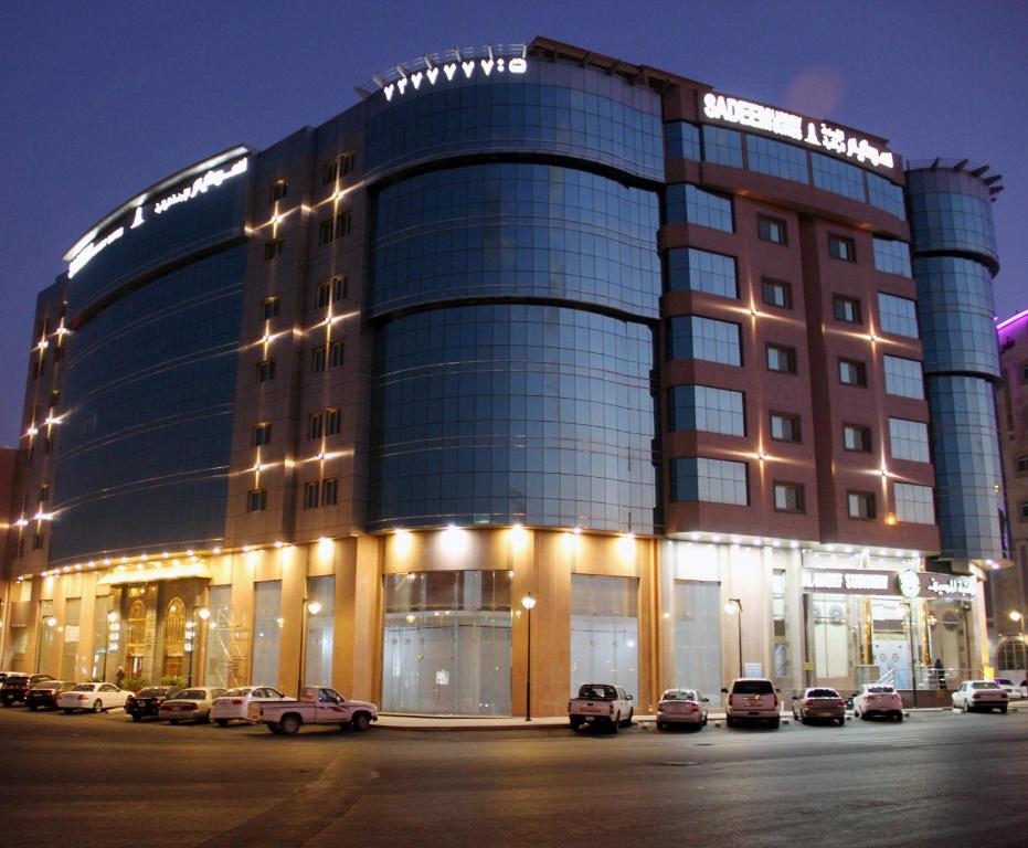塔伊夫萨迪姆阿尔法套房酒店的停车场内停放汽车的大型建筑