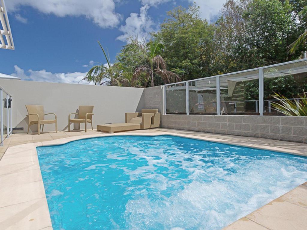 萨拉曼德湾Oaks Pacific Blue 516 private pool aircon WI-FI的一个带椅子的大型游泳池和一个庭院