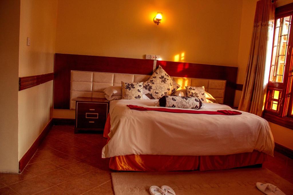 阿鲁沙New Charity Hotel International的卧室配有一张床,地板上配有2个拖鞋