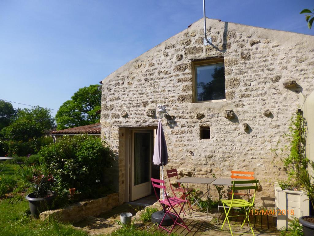 Coulonges-sur-lʼAutizeLa Remise的石头小屋设有桌椅,位于外面