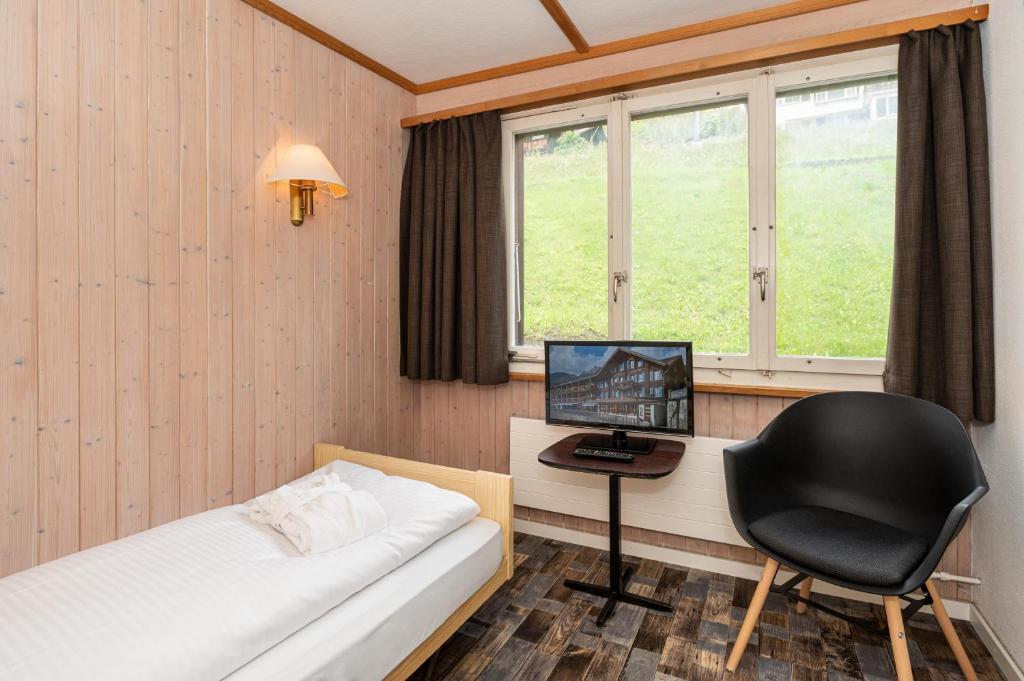 格林德尔瓦尔德少女峰小屋基本客房旅馆的一间卧室配有一张床、一张桌子和一把椅子