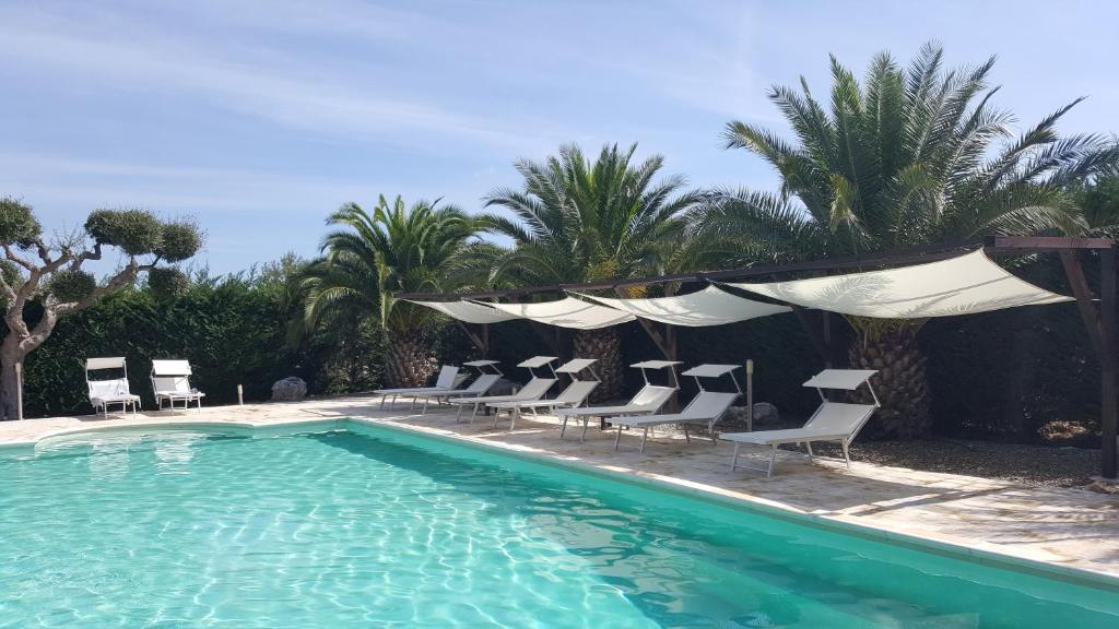 卡斯特拉纳格罗泰Masseria Cesarina B&B的一个带椅子的游泳池和一组棕榈树