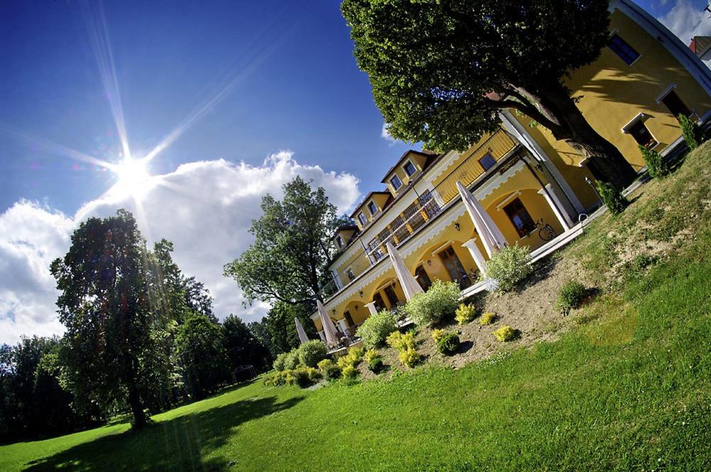 Lučivná鲁西福纳卡斯蒂尔酒店的一座黄色的大建筑,位于一座有阳光的草地山丘上