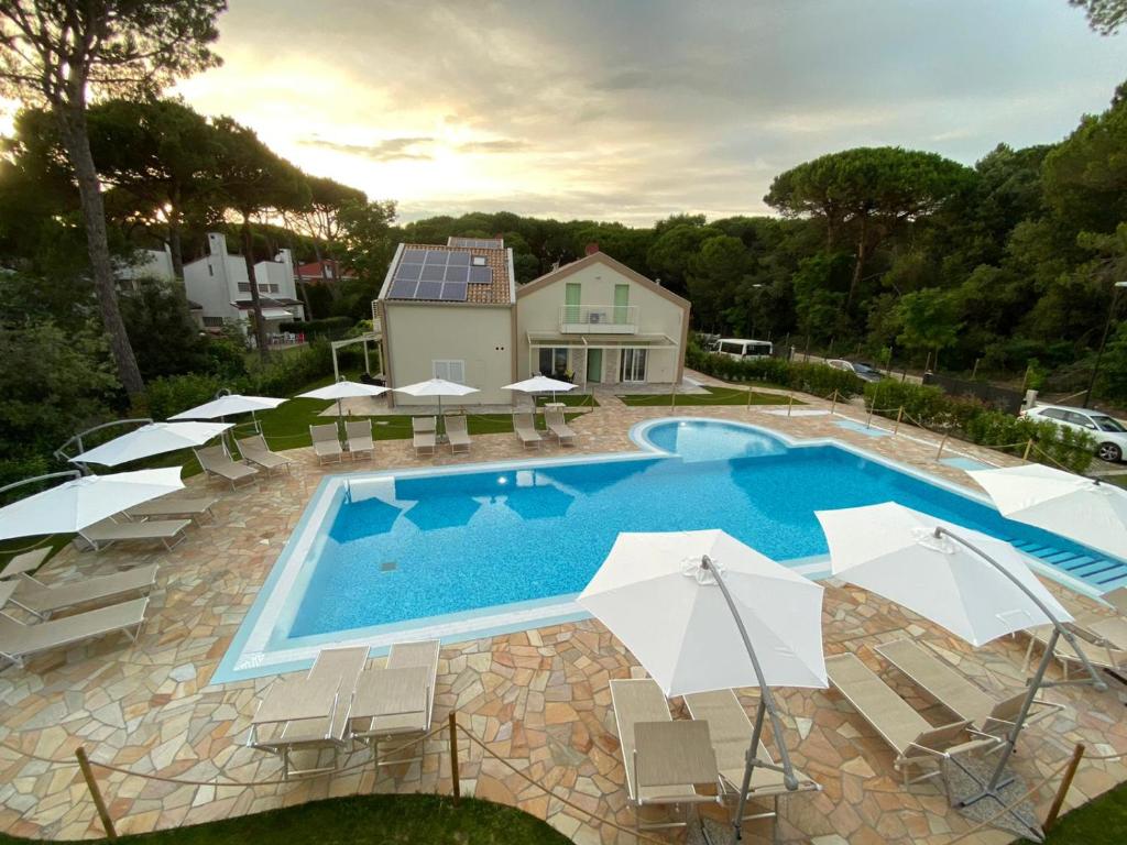 利多迪耶索罗Le Dune Verdi的房屋旁的游泳池配有椅子和遮阳伞