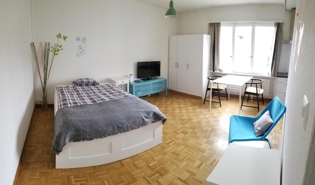 伯尔尼HSH Breitenrain - Serviced Apartment - Bern City by HSH Hotel Serviced Home的一间卧室配有一张床和一张蓝色椅子