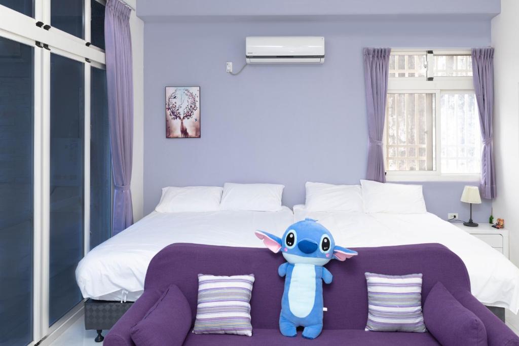 寿丰菓香101民宿fruity101的卧室里有一个蓝色的填充动物坐在床上