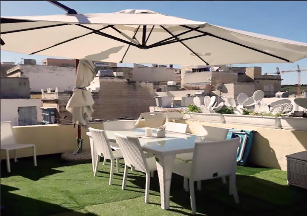 科斯皮夸Corto Maltese Guest House的屋顶上一把伞下的白色桌子和椅子