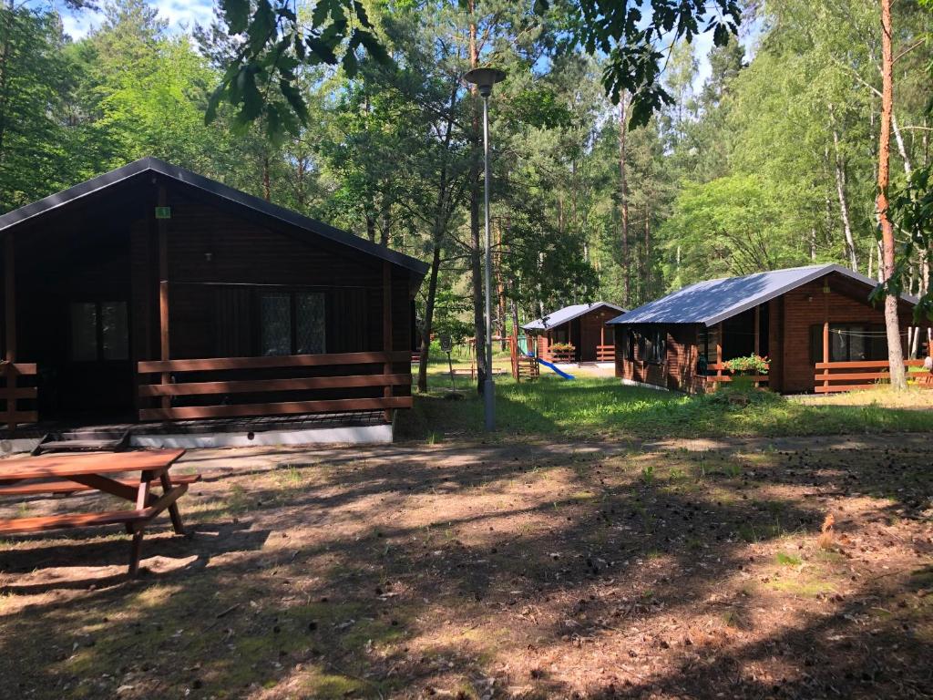 斯蒂格纳Leśnik Bungalow Stegna - domki letniskowe nad morzem的树林中的小屋,设有长凳和游乐场