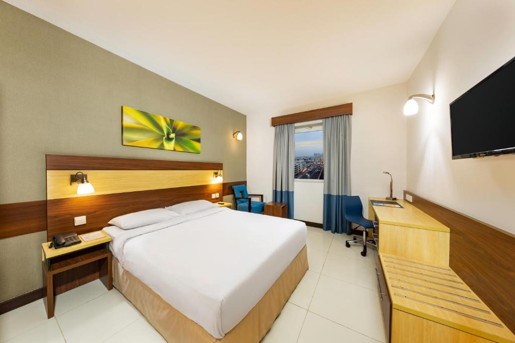 沙迦沙迦城市麦克斯酒店的酒店客房配有一张床、一张书桌和一台电视。