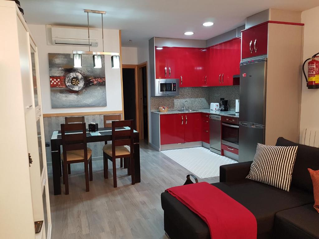 特鲁埃尔Apartamentos Turísticos "El Jardín"的厨房以及带红色橱柜和桌子的客厅。