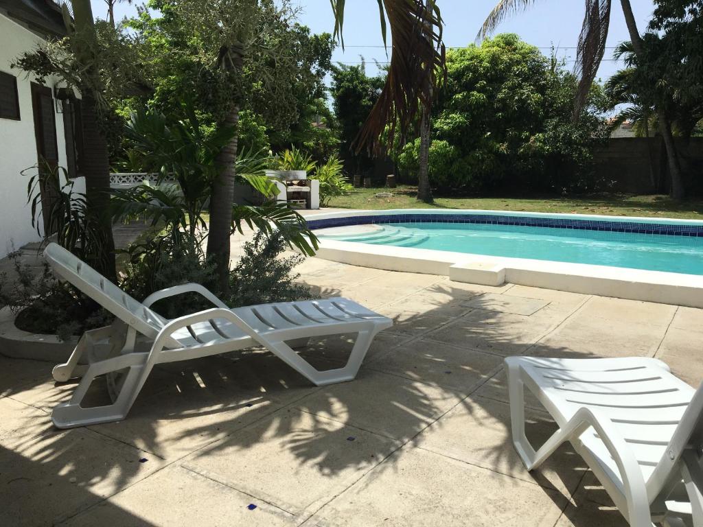拉纳韦贝Reef Winds Villa的两把躺椅和一个位于房子前的游泳池