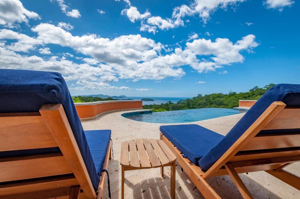 瓜纳卡斯特Ocean-View Villa Above Potrero Overlooking Two Bays的一个带两把椅子的庭院和一个游泳池
