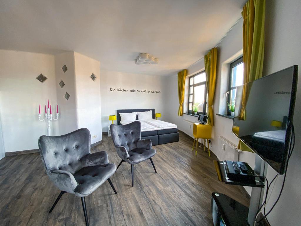 马格德堡apartHOTEL Magdeburg的一间卧室配有一张床、两把椅子和电视