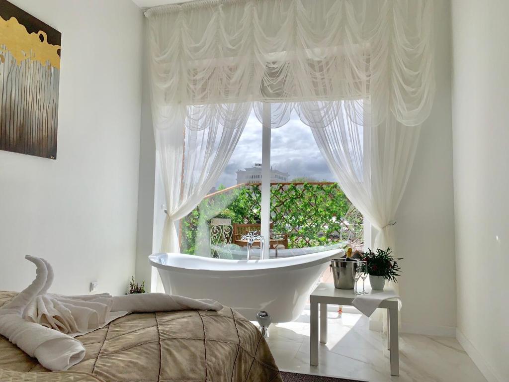 乌斯季卡缅诺戈尔斯克7 Boutique Hotel的卧室设有大窗户、浴缸和床。