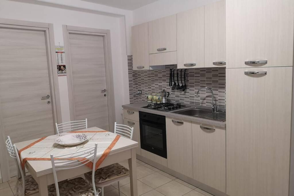 基亚拉蒙泰-古尔菲Lalù的厨房配有白色橱柜、桌子和水槽。