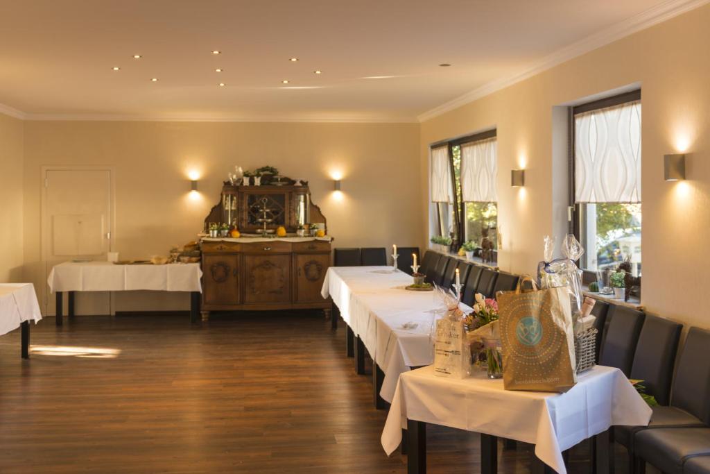 Überherrn哈斯菲尔德餐厅酒店的餐厅设有白色的桌椅和窗户。