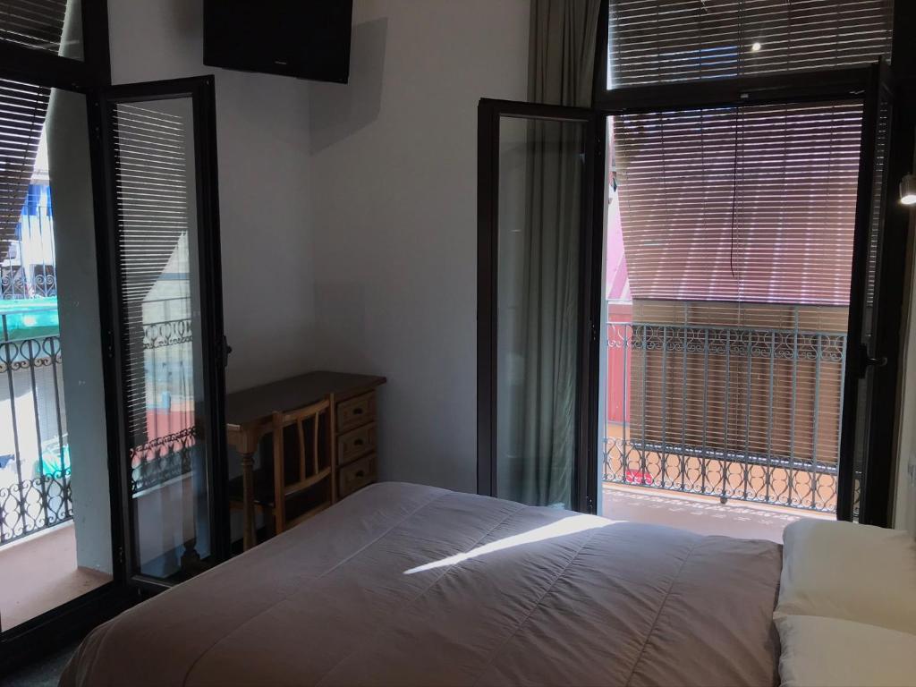 巴塞罗那Hostal Radio Barcelona的一间卧室设有一张床和两个大窗户