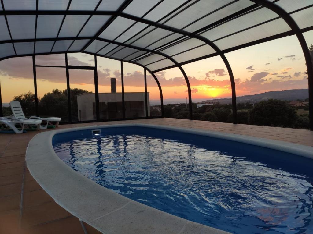 特鲁埃尔Casa Rural El Coscojar的屋顶下的游泳池,背景是日落