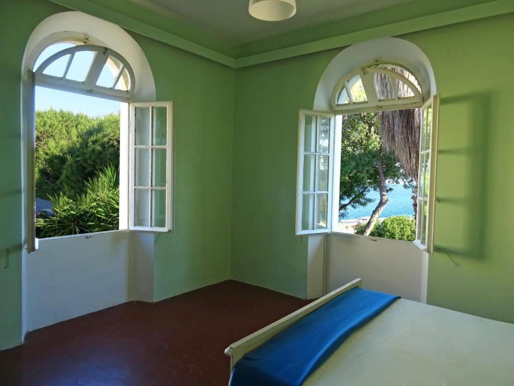 罗德镇Romantic rooms with stunning sea view的一间卧室设有2个窗户和一张蓝色床单。