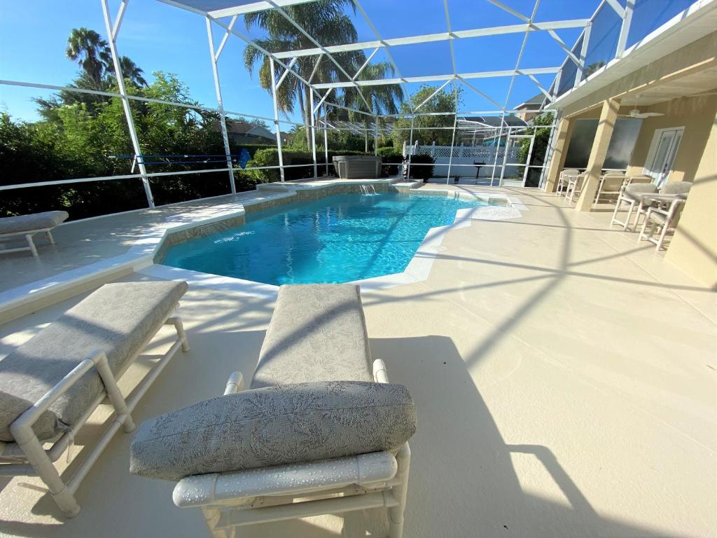 奥兰多Mickeys Pearl - Phenomenal 7BR with 4 Master Suites Privacy Pool & Hot Tub Gas BBQ - 2 miles to Disney的一个带2把躺椅和躺椅的游泳池