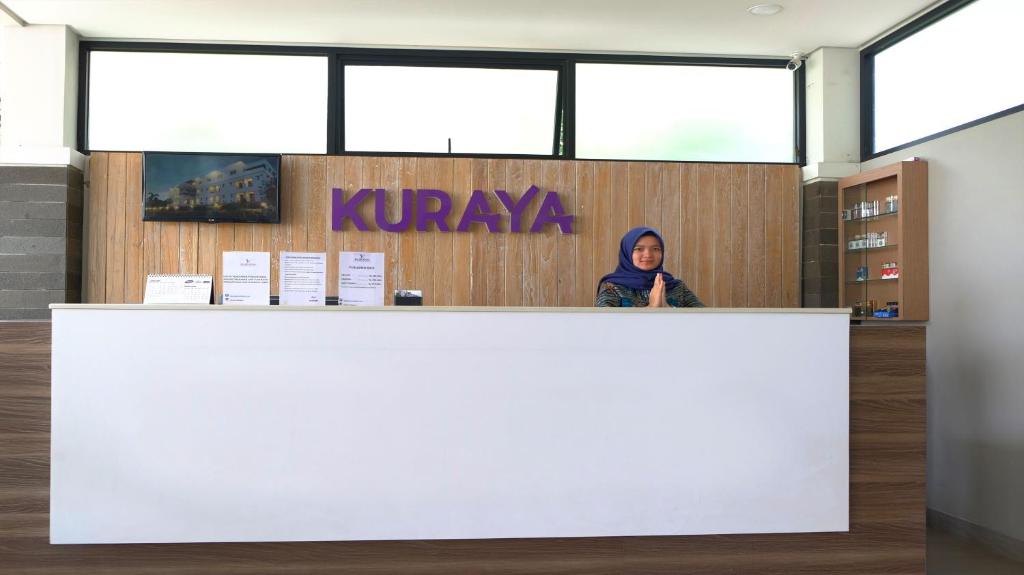班达楠榜Kuraya Hotel Residence的站在图书馆柜台后面的女人