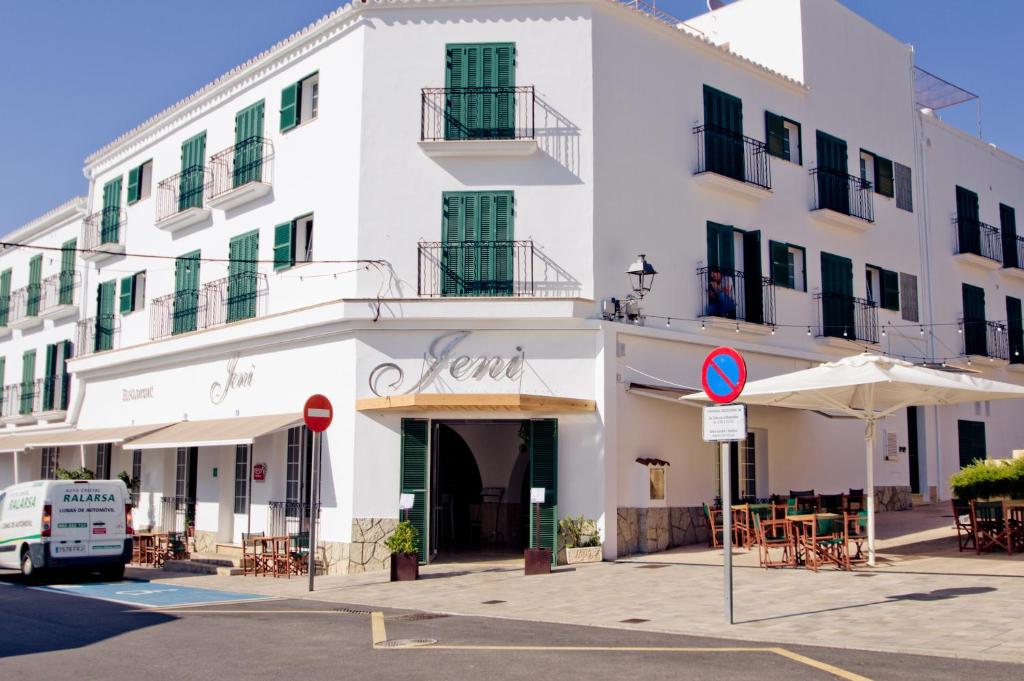 埃斯·梅卡达尔Hotel Jeni & Restaurant的街道上带桌子和遮阳伞的白色建筑