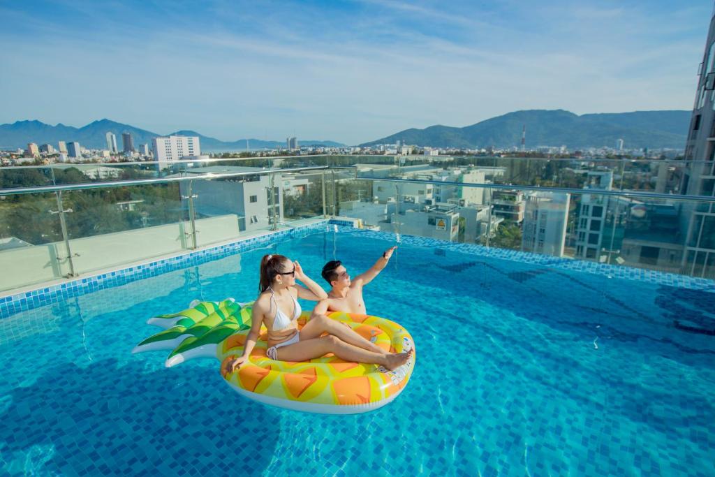 岘港Pharaoh Boutique Hotel Danang的两个女人坐在游泳池的内胎里