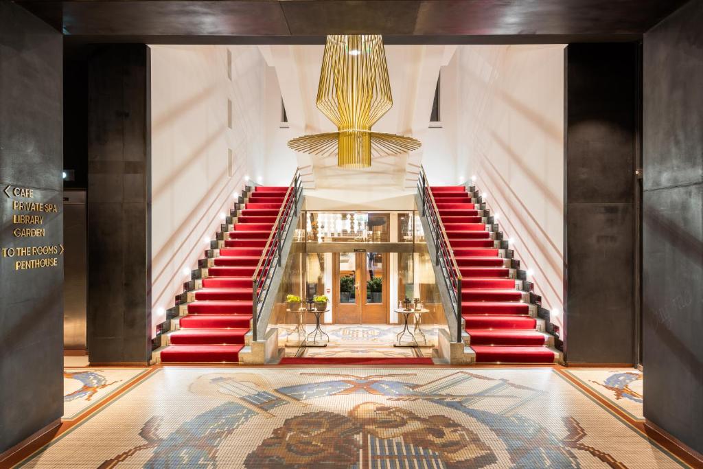 布拉格MOSAIC HOUSE Design Hotel的楼里的一个楼梯,有红色的楼梯和地毯