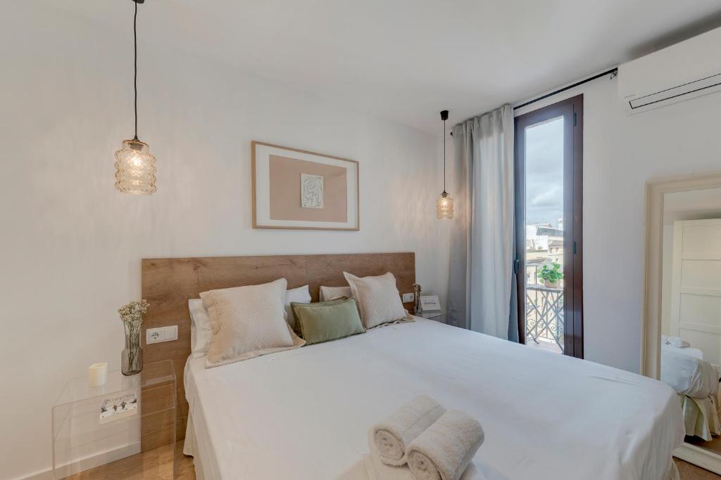 巴塞罗那快乐公寓的一间带一张白色大床的卧室和一个阳台