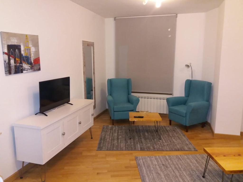 萨龙Saron Centro 1的客厅配有2把蓝色椅子和平面电视