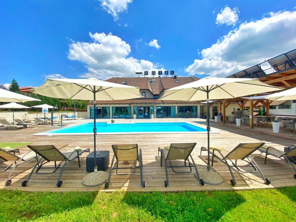 格拉博瓦茨16湖泊酒店的一组椅子和遮阳伞,位于游泳池旁