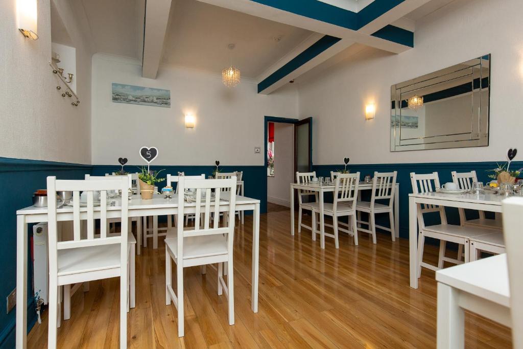 布莱克浦卡尔顿酒店的用餐室配有白色的桌子和白色的椅子