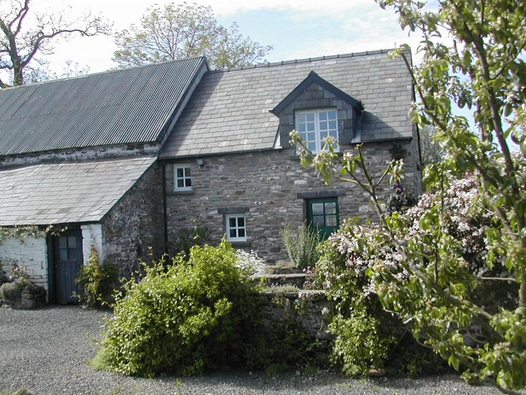 布雷肯Alltybrain Farm Cottages and Farmhouse B&B的一座带 ⁇ 顶的古老石头房子