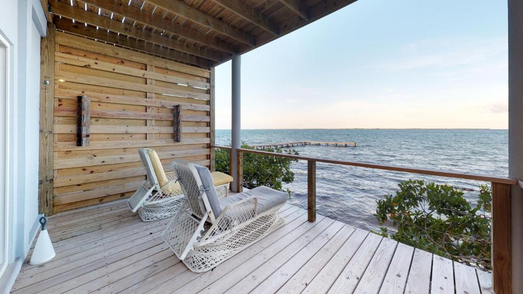 霍普金斯Thatch Caye Resort a Muy'Ono Resort的两把藤椅坐在俯瞰着大海的甲板上