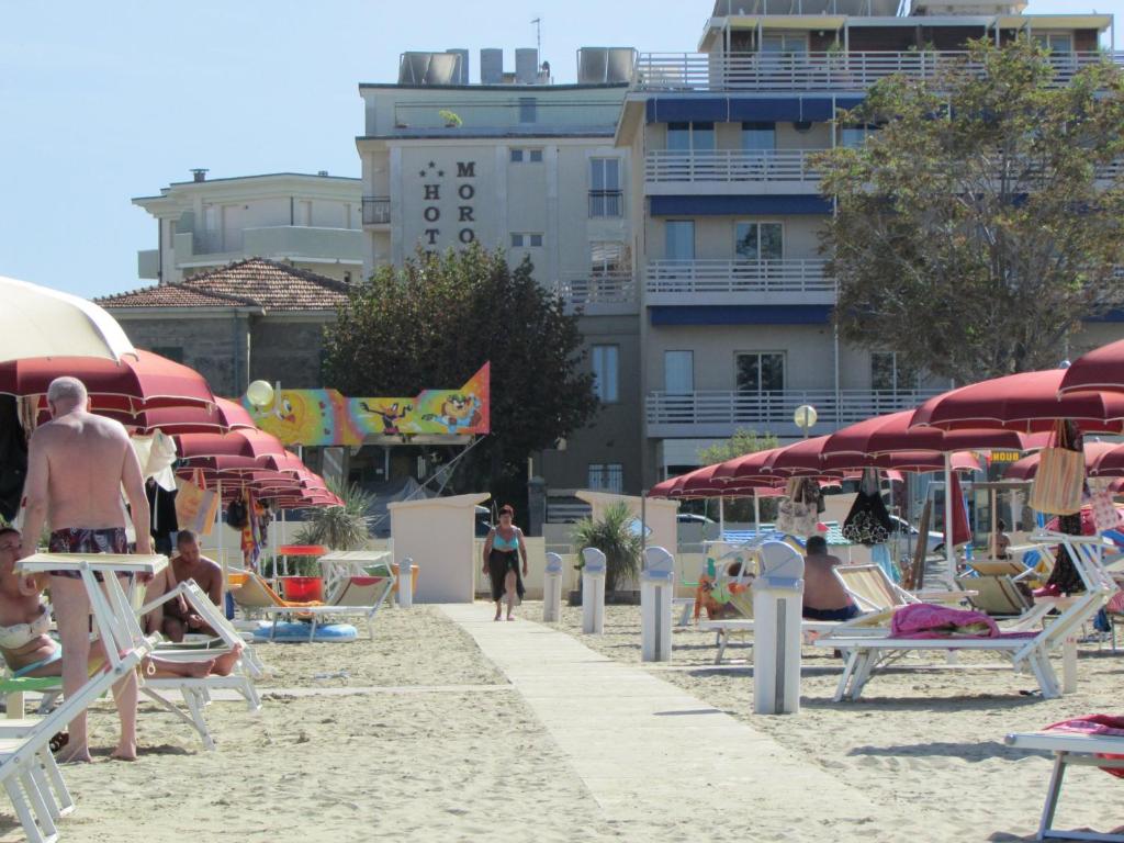 里米尼Hotel Morolli的海滩上有人坐在椅子和遮阳伞上