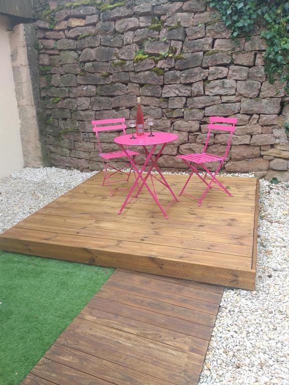 埃圭斯海姆Gîte le Petit Muscat à Eguisheim的木甲板上配有2把粉红色的椅子和一张桌子