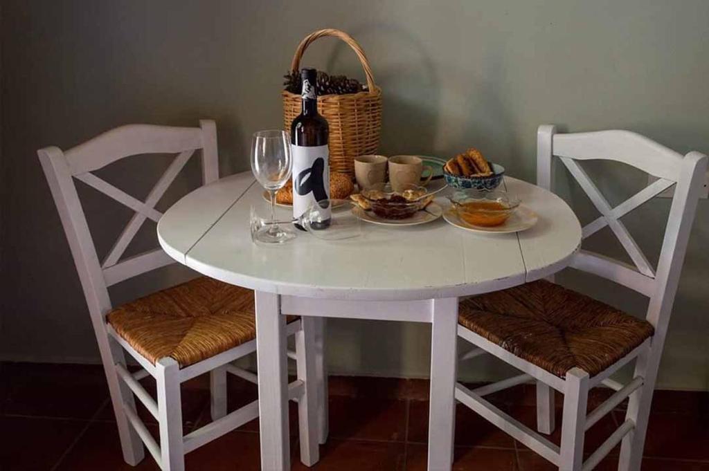 迈萨纳''Arsinoe'' cosy guesthouse的一张带两把椅子的白色桌子和一瓶葡萄酒
