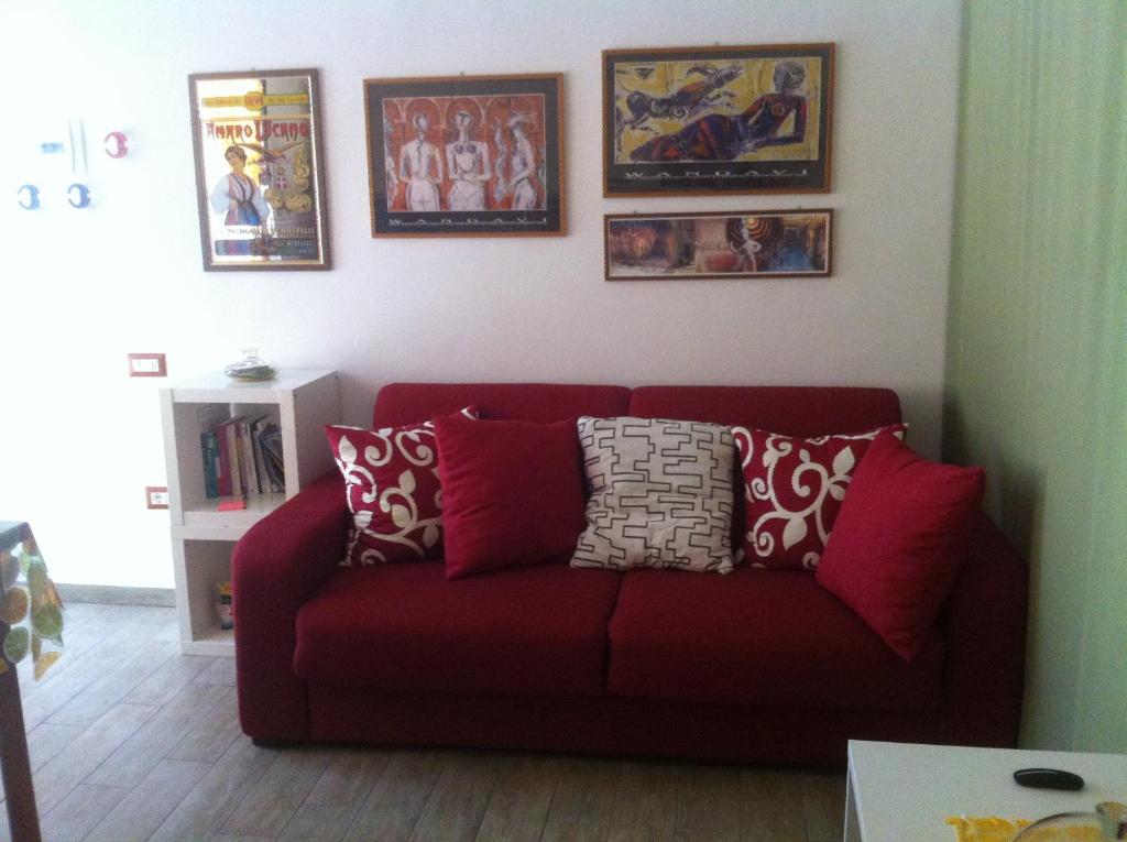马泰拉La Casa del Giglio的客厅里一张红色的沙发,墙上挂着照片