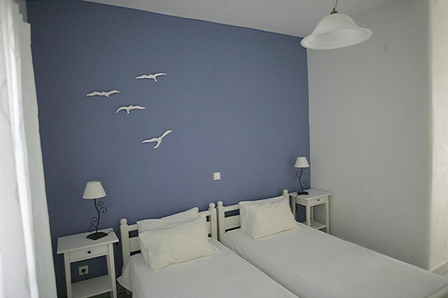 纳乌萨索菲别墅酒店的卧室配有两张床,墙上有白色鸟