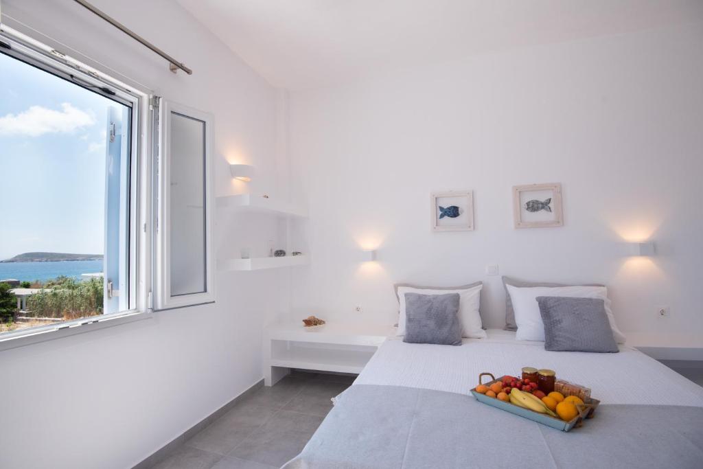 克里希阿克提弗洛拉及阿基洛斯一室公寓的白色的卧室,配有一张带水果盘的床