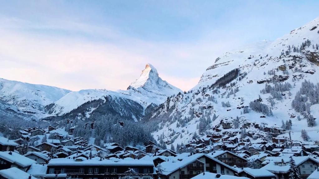 采尔马特摩羯座酒店 的山地,有积雪覆盖,有城镇和建筑