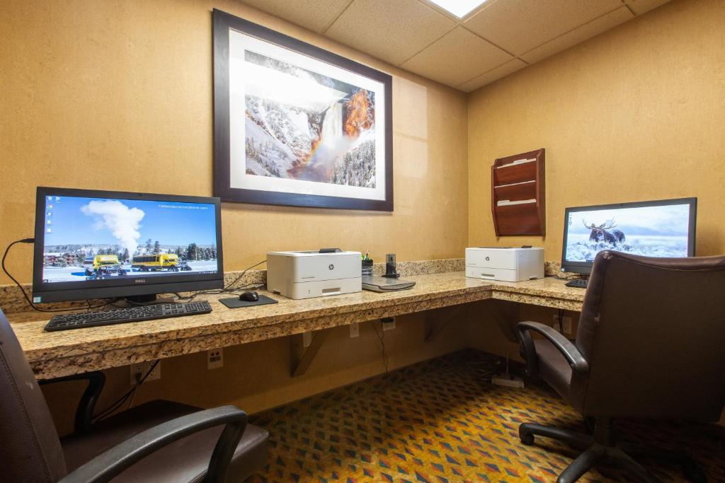 西黄石西黄石假日酒店的书桌上有两个电脑显示器的房间